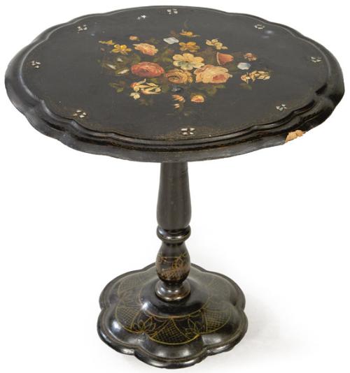 Mesa auxiliar victoriana, con tapa abatible de perfil ondulado en papier mache lacado en negro y decoración pintada de flores y nacar, sobre pedestal en madera torneada. Faltas