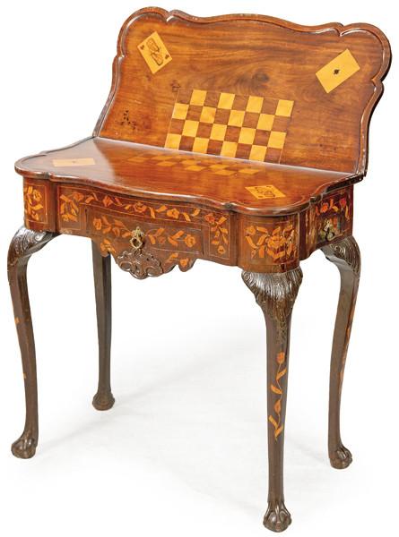 Mesa de juego en madera de nogal con decoración de marquetería de motivos vegetales, posiblemente realizadas posteriormente. Con tapa abatible que al abrirse revela una superficie con damero y cartas en marquetería. Holanda, segunda mitad S. XVIII