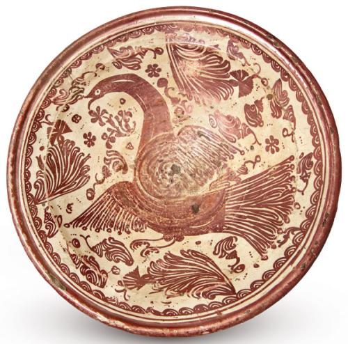 Plato hondo de loza, decorado con reflejo metálico de color cobrizo sobre cubierta de plomo traslúcida.