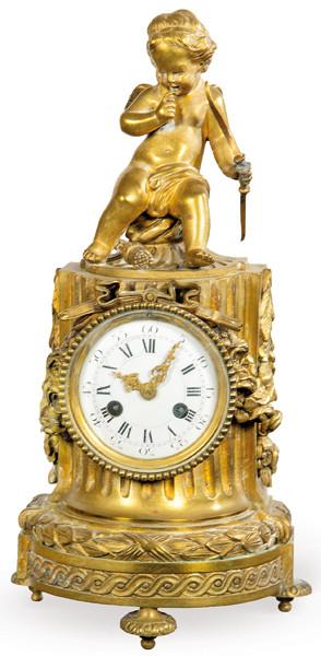 Reloj de mesa Napoleón III, estilo Luis XVI en bronce. Sobre basamento en forma de columna clásica en la que se aloja la esfera del reloj rodeada de guirnaldas de flores