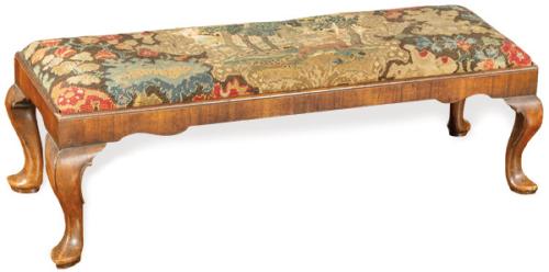 Banqueta Jorge II en madera de nogal tallada, con patas rematadas en "padfood", y tapicería bordada con escena de caza rodeada por motivos florales. Faltas.