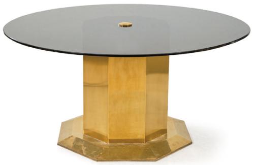 Mesa de comedor con tapa circular de cristal negro, sobre pedestal hexagonal de latón.