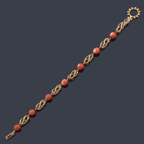 Pulsera con siete bolitas de coral y motivos calados en oro amarillo de 18K.