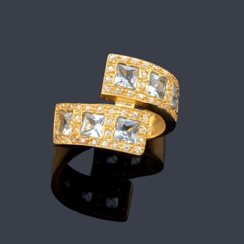 Anillo con dos brazos contrapeados con seis topacios azules y símil de brillantes.