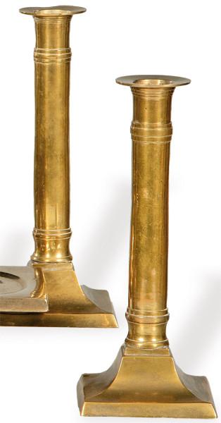 Pareja de candeleros de bronce, con vástago de columna y base cuadrangular, España h. 1800.