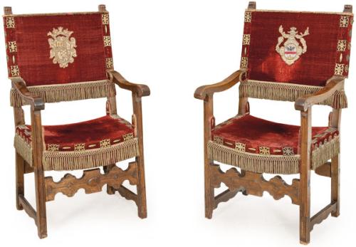 Pareja de sillas de brazos en madera de nogal. Sobre patas estriadas unidas por una chambrana central recortada y moldurada. Los brazos son ligeramente curvos.