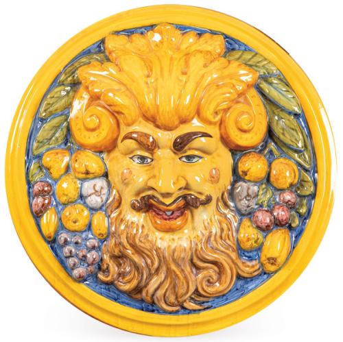 Placa para fuente, representando la cabeza de un Fauno rodeado de frutas en relieve. Realizada en cerámica pintada y esmaltada.