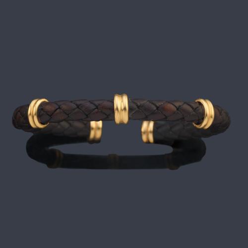 Pulsera semirrígida realizada con cuero trenzado y detalles en oro amarillo de 18K.