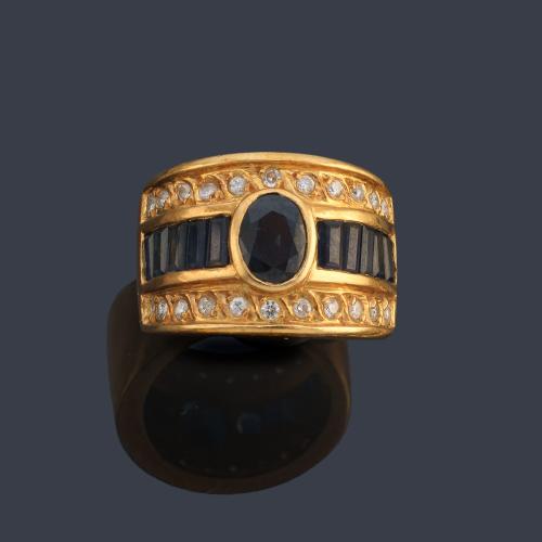 Anillo con zafiro talla oval y calibrados con doble banda de brillantes, en montura de oro amarillo de 18K.