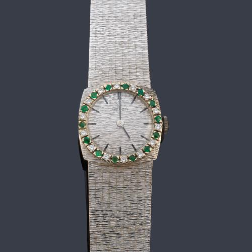 OMEGA de señora con caja y brazalete en oro blanco de 18 K con orla de brillantes y esmeraldas.