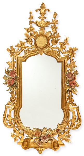 Espejo de estilo barroco, realizado en madera tallada, dorada y policromada, con profusa ornamentación floral y rocalla.