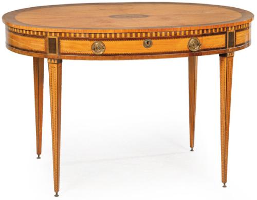 Mesa de centro ovalada Jorge III en madera satin y caoba, con decoración de marquetería de motivos geométricos, un cajón en la cintura con tiradores y escudo de cerradura en latón. Inglaterra, principios S. XIX