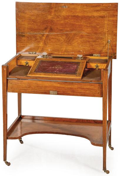 Mesa escritorio Eduardina en madera de caoba con decoración embutida de maderas frutales. Tapa abatible que al abrirse revela un interior con superficie para escribir así como dos cajones y tinteros. Inglaterra, finales S. XIX