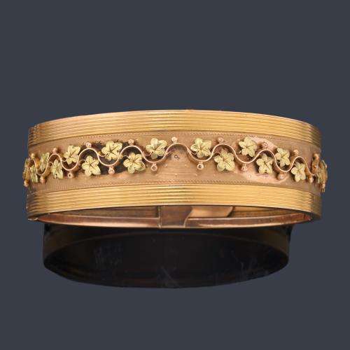 Pulsera ancha y rígida con motivo central vegetal en oro rosa y verde de 18K sobre montura de oro amarillo de 18K. S. XIX.