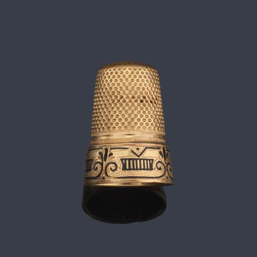 Dedal en oro amarillo de 18K decorado con motivos de roleos en color azul. Con estuche original.