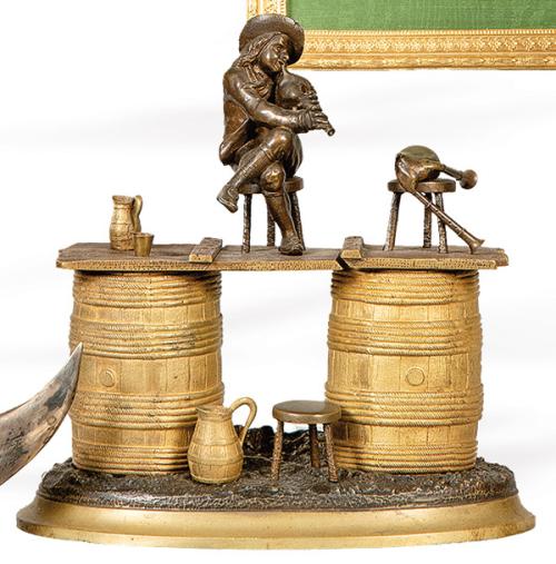Tintero de bronce dorado y patinado, representando a un gaitero tocando sobre dos barriles, Francia S. XIX.
