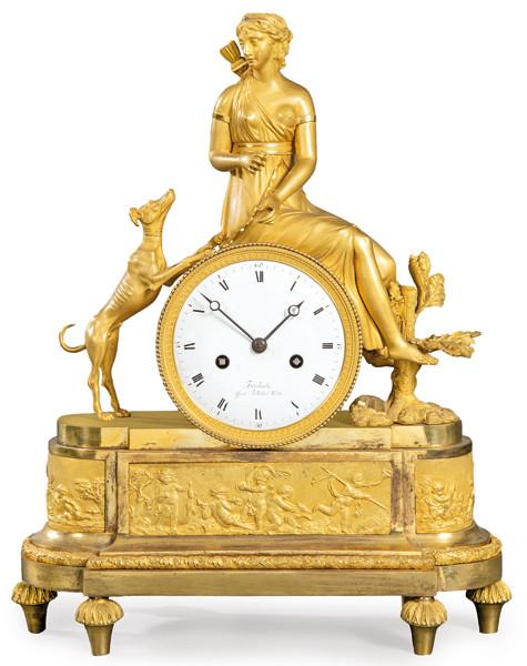 Reloj de sobremesa imperio en bronce dorado. Sobre basamento elíptico se sitúa la esfera del reloj, firmada Brisbart con númeración romana. Encima de ella, Diana cazadora.