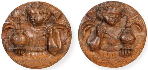 Pareja de tondos de madera de palosanto tallada en relieve "Amorcillos con Tintero y Pluma", S. XIX.