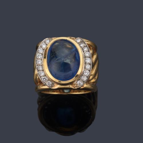 Anillo con zafiro central talla cabujón de aprox. 9,12 ct con dos bandas curvadas de brillantes.