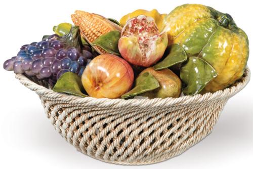 Centro de mesa en forma de cesta calada con calabazas, granadas, manzanas, maíz y uvas, en cerámica moldelada, pintada y esmaltada.