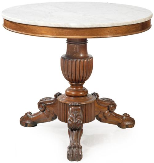 Mesa de centro Imperio, con tapa circular en mármol blanco, sobre pedestal abalaustrado tallado en madera de caoba. Y sujetada por patas en forma de garra de animal. Francia, primer tercio S. XIX
