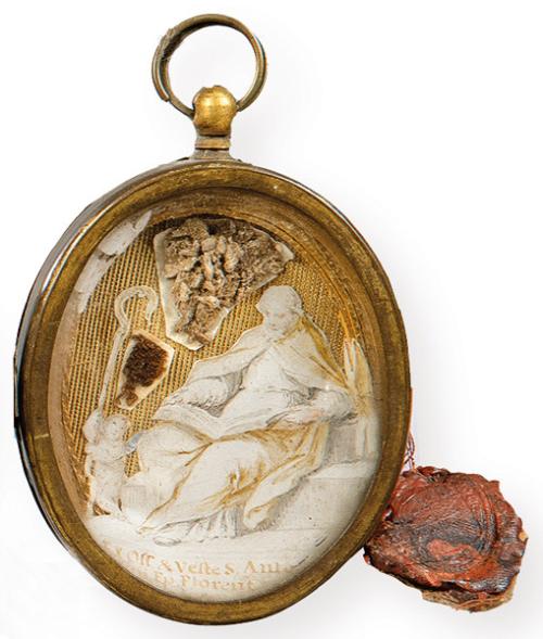 Relicario de metal con recortable de un Santo con libro pintado y reliquieas oseas y textiles, España h. 1800.