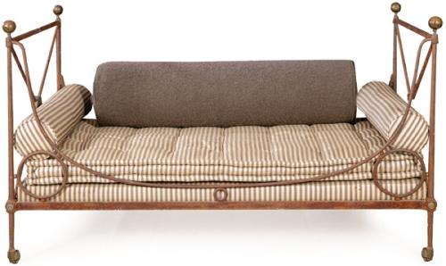 Cama de día con estructura en hierro forjado y ensamblado, acabado en pátina oscura; ruedas originales de fundición metálica. Colchonería y cojinería modernas en tela de algodón de rayas.