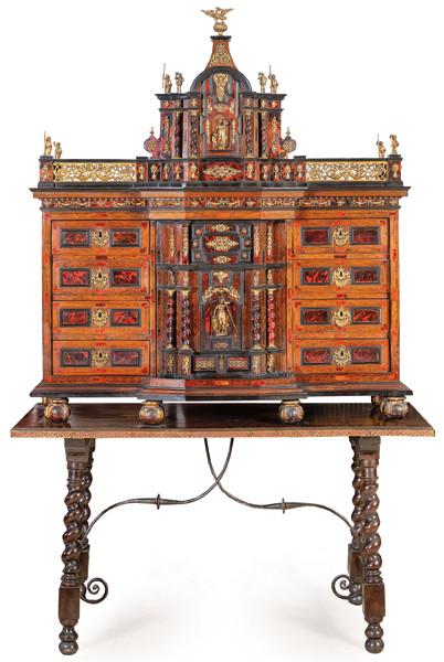 Contador estilo Carlos II en madera de nogal, madera ebonizada y placas de carey, con aplicaciones de bronce. Sobre mesa de época posterior, con patas de torneado salomónico y fiadores abalaustrados de hierro.