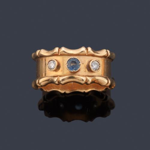 Anillo ancho con dos brillantes y zafiro central en montura de oro amarillo de 18K.