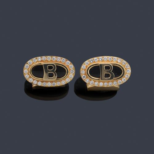 Gemelos con diseño ovalado con placa de ónix y orla de brillantes con 'B' central.