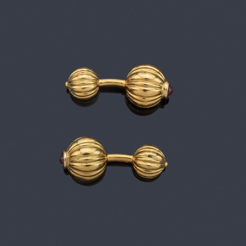 Gemelos con motivos esféricos gallonados con remate de rubíes talla cabujón, en montura de oro amarillo de 18K.