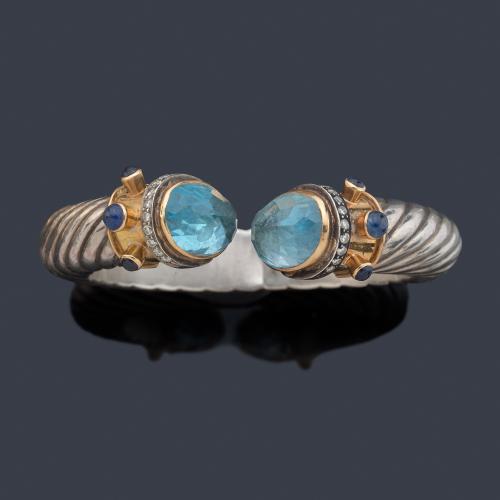 Pulsera con diseño entorchado con dos topacios azules en montura de oro amarillo de 18K y plata.