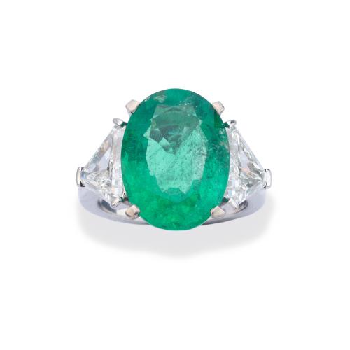 Anillo con importante esmeralda talla oval de aprox. 8,09 ct con dos diamantes talla triángulo de aprox. 3,18 ct en total. Certificado C. Dunaigre Switzerland.