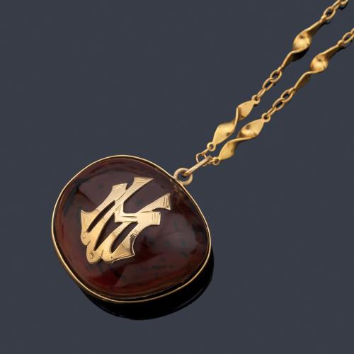 Colgante realizado con semilla y motivo de signo horóscopo libra y dos iniciales en oro amarillo de 18K.