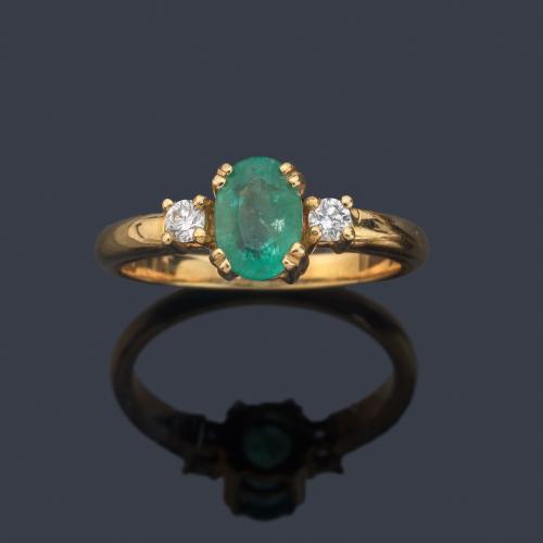 Anillo con esmeralda talla oval y dos brillantes en montura de oro amarillo de 18K.