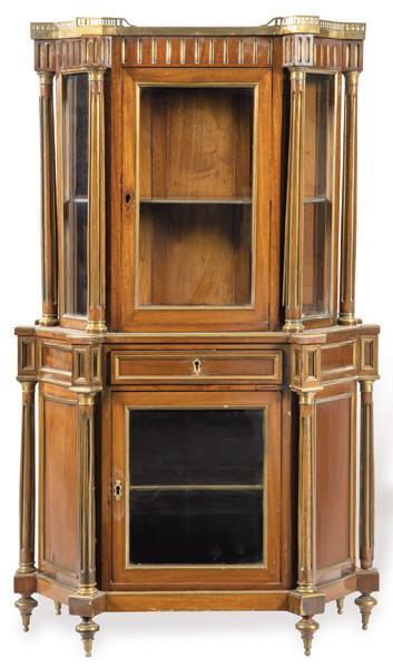  Vitrina estilo directorio en madera de caoba de forma poligonal con columnas clásicas de dos cuerpos y aplicaciones en metal dorado. Tapa superior en mármol blanco.