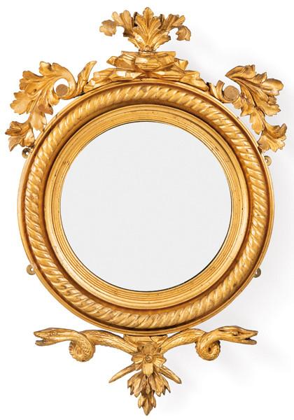 Espejo Regencia con marco tallado y dorado. Presenta estructura ovalada clásica con ornamentación de hojas de acanto y volutas simétricas en el remate superior e inferior, íntegramente en madera tallada y dorada.