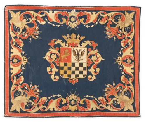  Repostero con escudo central sobre campo azul en lana, enmarcado por motivos vegetales en rojo y dorado.