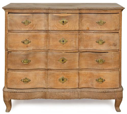 Cómoda rococó en madera de roble con cuatro cajones con perfil tipo "ballesta", sobre patas ligeramente curvas. Tiradores y escudos de cerradura en bronce. 