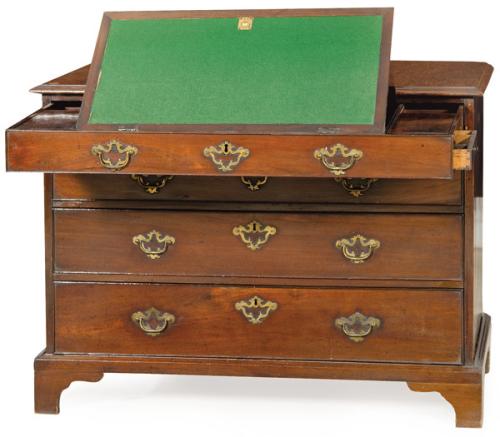 Cómoda escritorio Jorge II en madera de caoba con tiradores y escudos de cerradura en bronce. El cajón superior al abrirse se convierte en un escritorio con tapa abatible, cajones secretos y compartimentos. Inglaterra segundo tercio S. XVIII