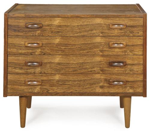 Cómoda con estructura rectangular en madera de palisandro, cuatro cajones superpuestos, tiradores cilíndricos macizos de palisandro, elevada sobre cuatro patas cónicas torneadas.