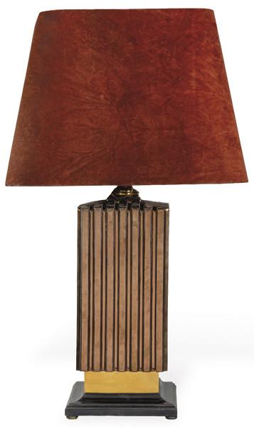 Lámpara de mesa en cerámica moldeada y estructurada en planos verticales acanalados, esmaltada en tono rojo burdeos con reflejo metálico; sobre base cuadrangular en madera lacada en negro. Pantalla de tela. S. XX