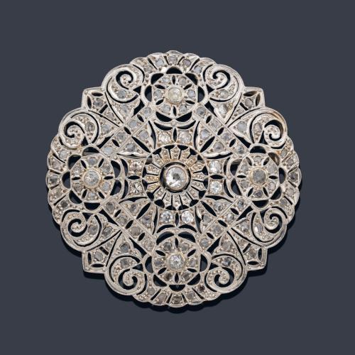  Broche circular con diseño calado con diamantes talla rosa y antigua, realizado en montura de oro blanco de 18K.