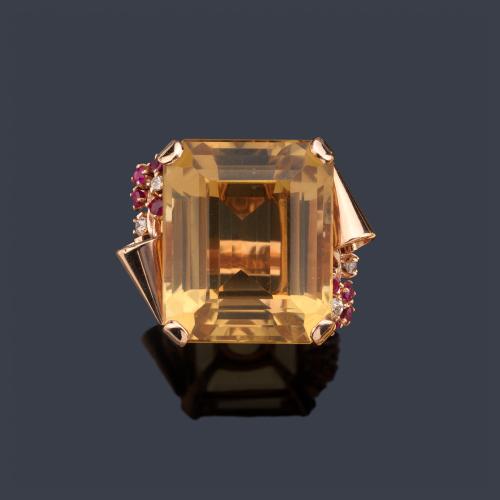  Anillo de cocktail con gran cuarzo citrino central, con detalles de roleos en ambos lados, con rubíes sintéticos de aprox. 0,50 ct y diamantes de aprox. 0,10 ct en total. Años '70.