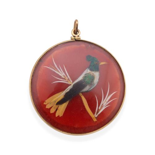  Colgante - medallón con dos motivos de aves con apliques de pluma de pavo real, sobre placa circular color rosado. S. XIX.