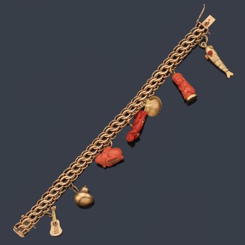  Pulsera con eslabones barbados con tres dijes de diferentes figuras realizadas en coral y cuatro realizadas en oro amarillo de 18K.