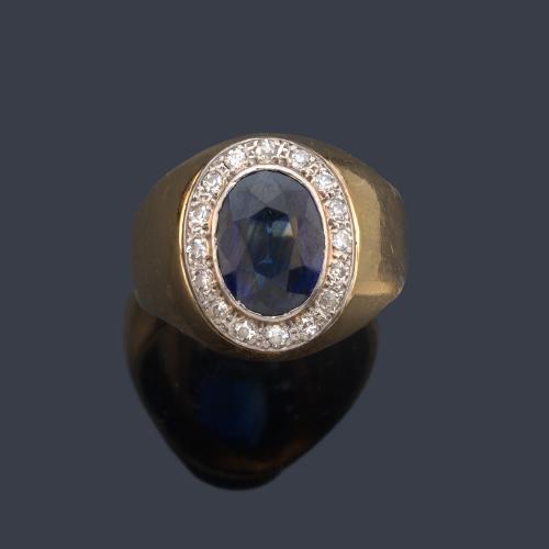  Anillo tipo sello con zafiro talla oval y orla de brillantes, en montura de oro amarillo de 18K.