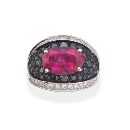  Anillo con turmalina rubelita talla oval sobre pavé de brillantes negros de aprox. 1,15 ct en total y dos bandas de brillantes incoloros de aprox. 0,72 ct.