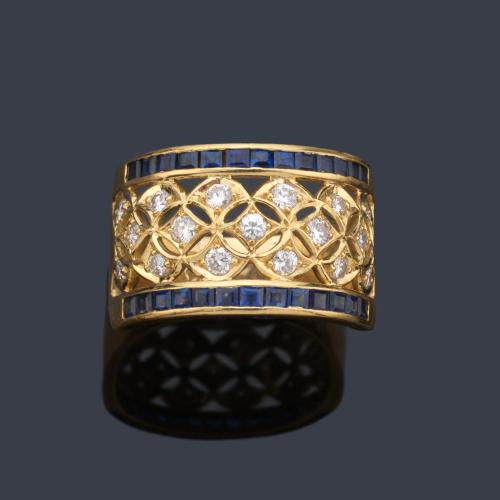 Anillo con diseño calado con brillantes y dos bandas zafiros calibrados, en montura de oro amarillo de 18K.