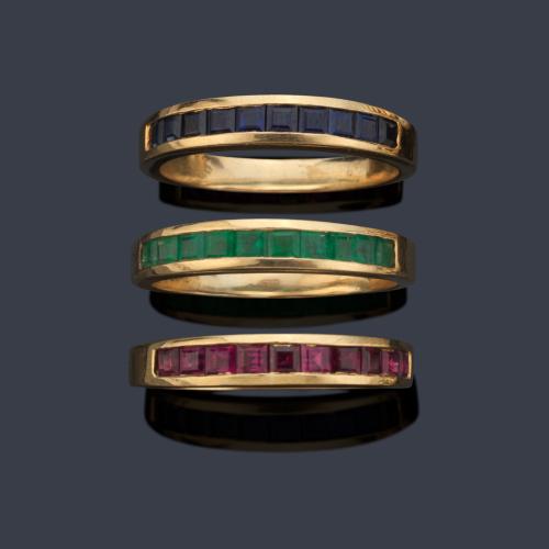 Tres anillos con banda de zafiros, esmeraldas y rubíes calibrados en montura de oro amarillo de 18K.